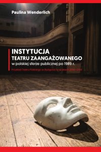 Na okładce w tle zdjęcie zabytkowej widowni w teatrze z perspektywy sceny, na której deskach leży symboliczna maska. Białe liternictwo i czerwone paski ozdobne